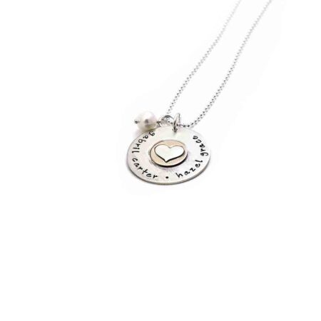 A sterling silver disc with hand stamped names. Layered with a gold-filled disc and a sterling silver heart in the middle.